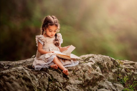 坐在岩石上看书的小女孩